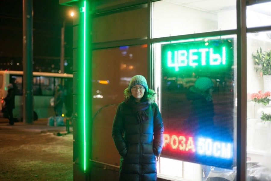 woman-wearing-black-bubble-coat-and-gray-knit-cap-standing-beside-building-with-led-signage-at-night