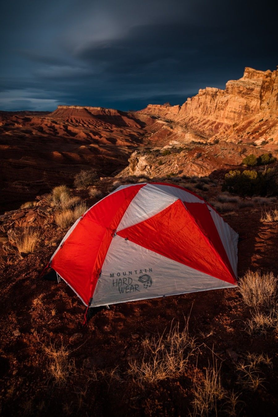 red-and-white-mountain-hard-wear-tent-on-ground-beside-rock-formation