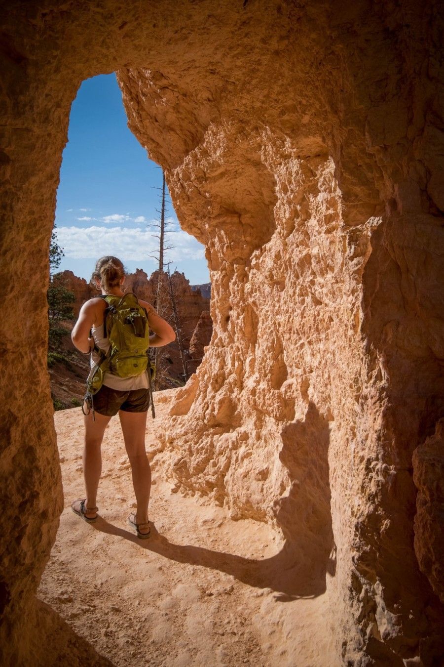 woman-carrying-backpack-standing-in-cave-passage