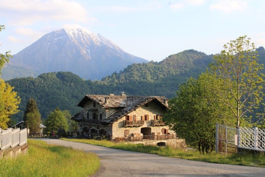 brick-house-near-road-and-trees-with-mountains-at-the-distance-during-day