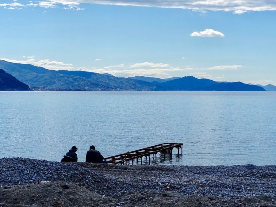 two-person-sitting-near-sea-dock-during-cloudy-day